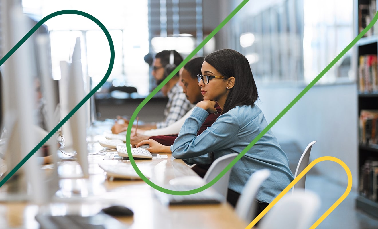 Three IT workers sitting in a row working on desktop computers